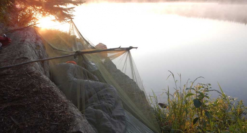 A person rests on a cliff high above a body of water. 